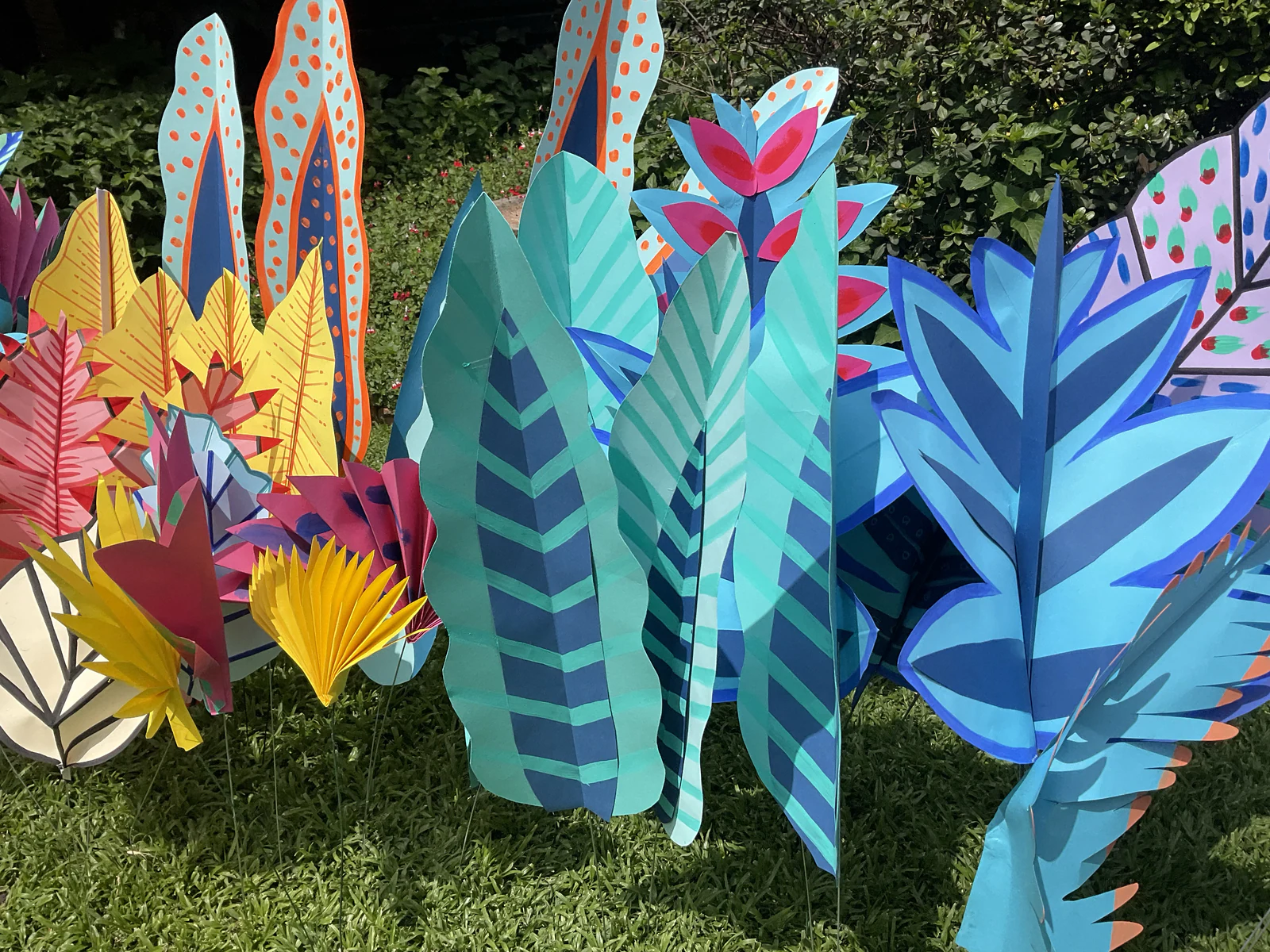 Close view of the painted leaf border in sunlight: teal chevron leaves, blue ferns, spotted spears and yellow fans