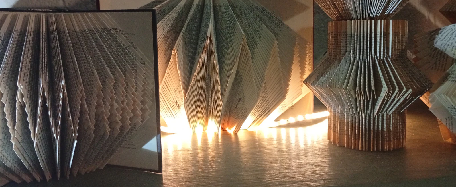 Lamps folded from the pages of old books, lit from inside